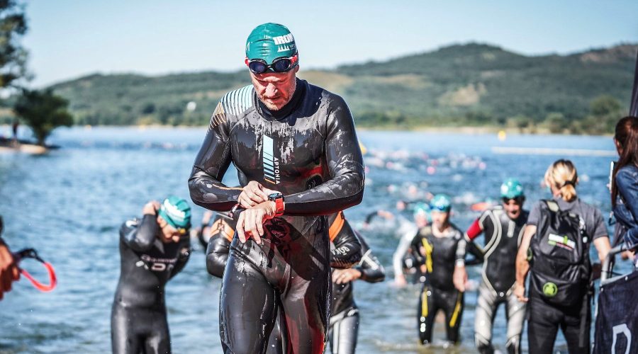 Petr vyléza v neoprenu z vody, sleduje sportovní hodinky